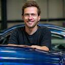 Client homme souriant devant véhicule brillant